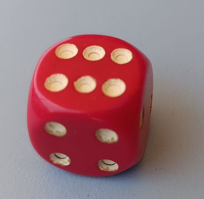 Ein roter Würfel mit sechs Seiten, auf denen die Punkte 1 bis 6 angeordnet sind.